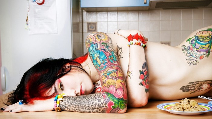 Tattooed woman lying on a kitchen counter