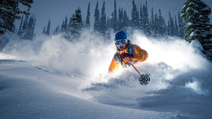 Skier in Orange Jacket Carving Through Snow