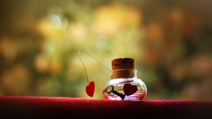 A tiny glass bottle with a cork stopper containing a key and a heart charm.