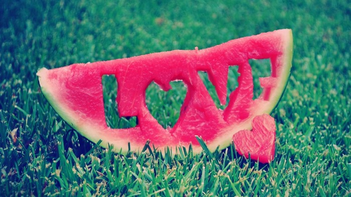 Watermelon slice with 'LOVE' carved out on grass