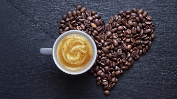 Heart shape made of coffee beans with a cup of coffee