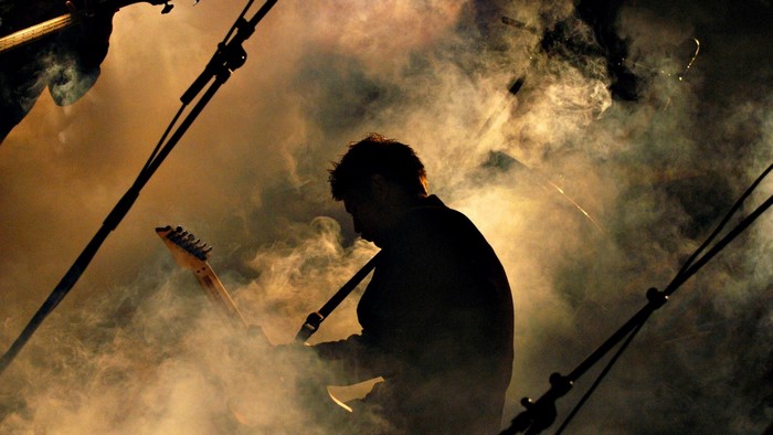 Guitarist playing guitar on stage with smoke