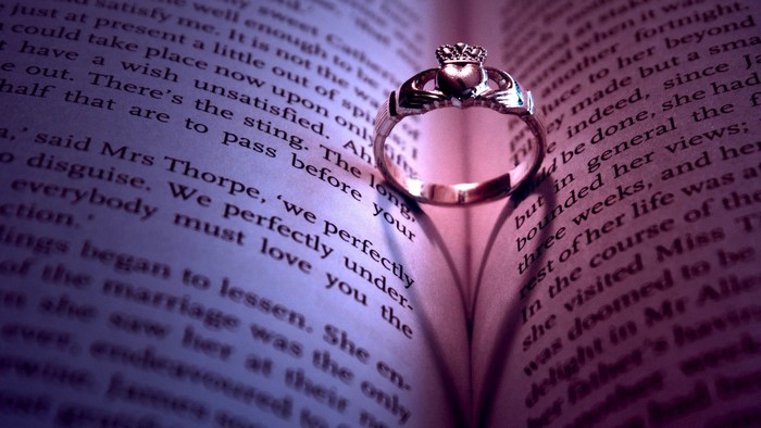 Claddagh ring casting a heart shadow on an open book