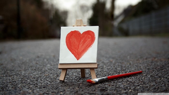 Painting of a red heart on a canvas with a paintbrush