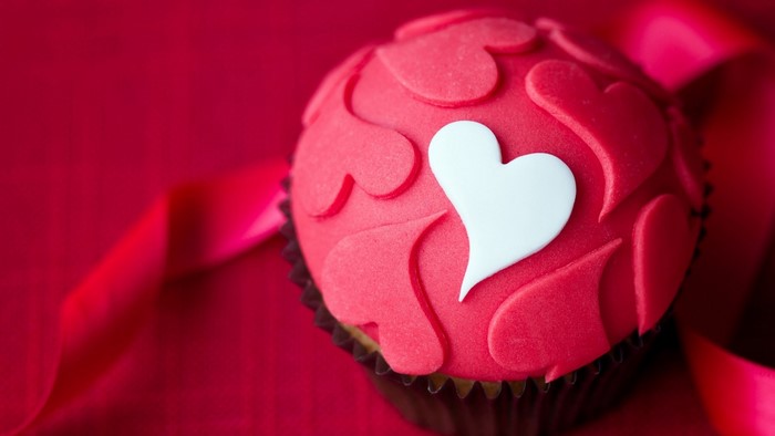 Red cupcake with heart decorations and ribbon