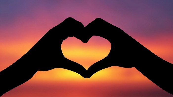 Silhouette of hands forming a heart at sunset