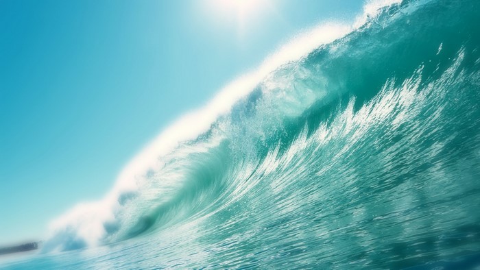 Ocean wave crashing under bright sun
