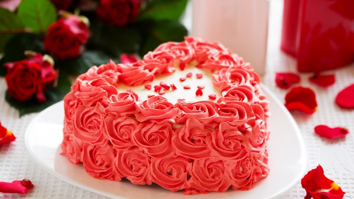 Heart-shaped cake with rose frosting and red roses