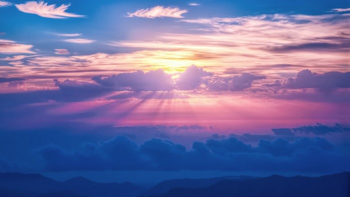 Sunrays shining through clouds over mountains