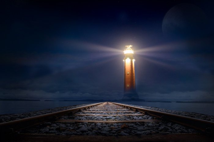 Lighthouse on railroad tracks at night