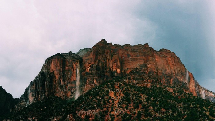 Mountain with multiple waterfalls under cloudy sky