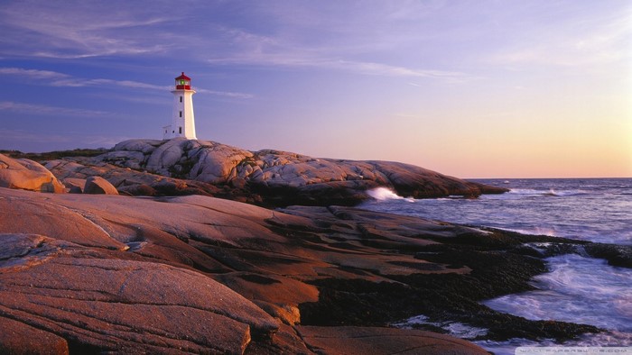 White lighthouse on rocky coast at sunset