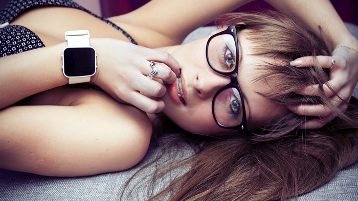 Girl with glasses posing on a bed