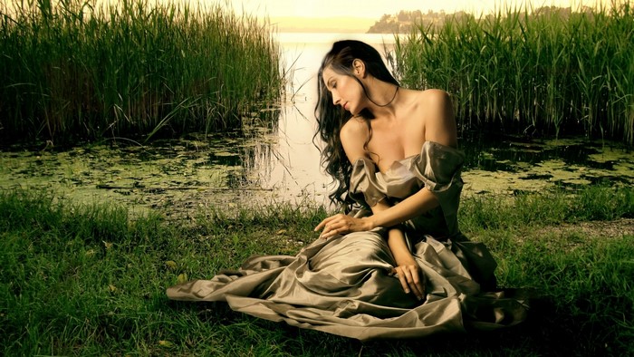 Woman in a flowing dress by a lake