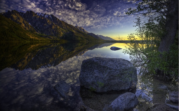 Mountain lake reflection at sunset with rocks
