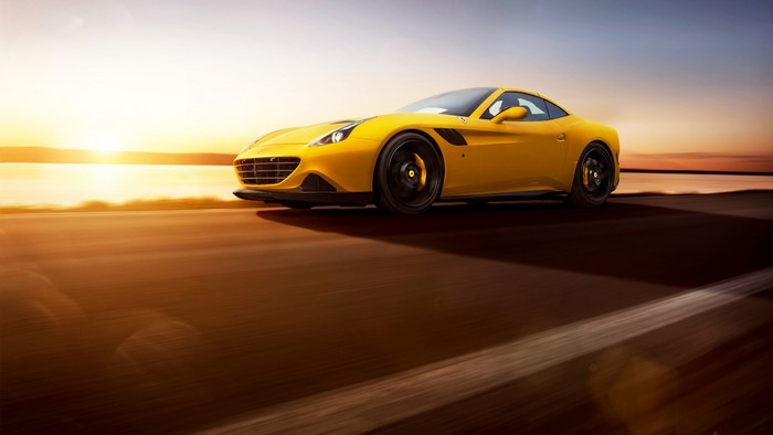 Yellow Ferrari California T driving at sunset