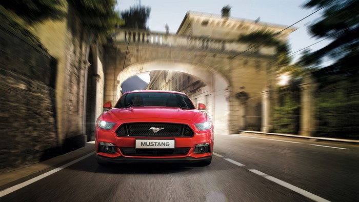 Red Ford Mustang driving through an archway