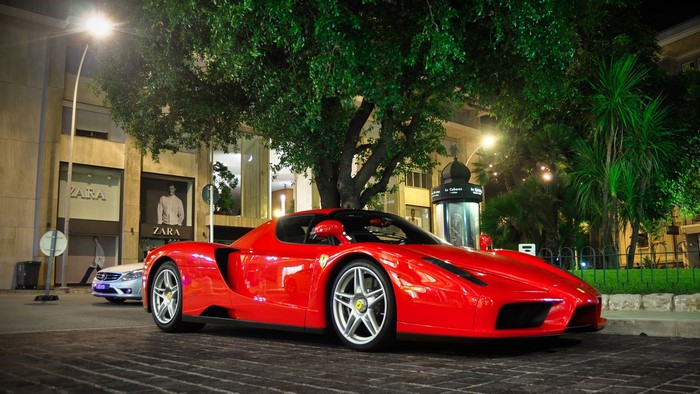 Red Ferrari Enzo parked on cobblestone street at night