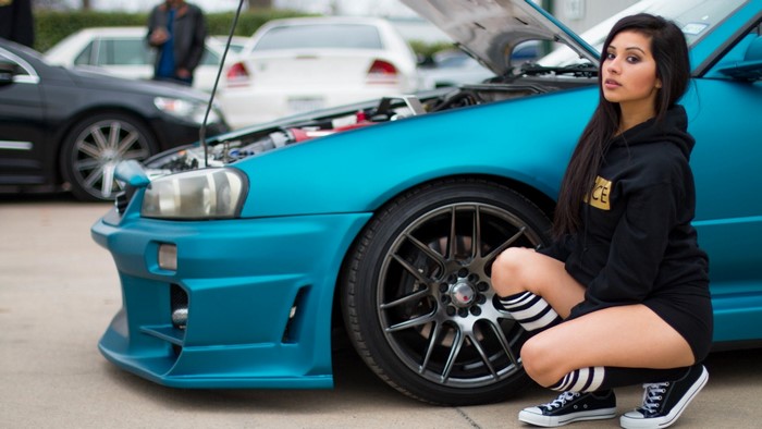 Girl in hoodie next to modified blue car
