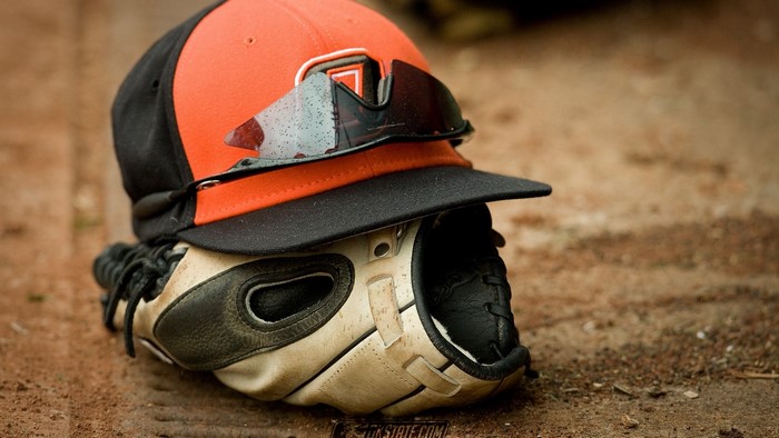 Baseball glove, cap, and sunglasses on dirt