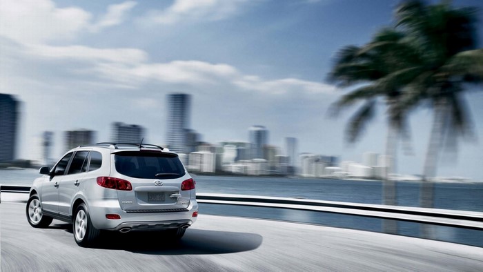 Silver Hyundai Santa Fe SUV driving by a city skyline