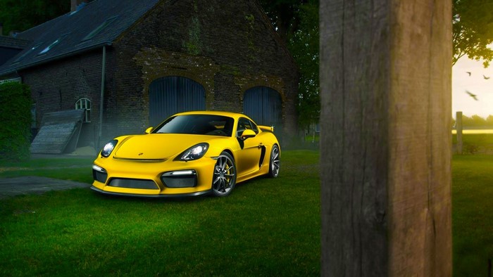Yellow Porsche Cayman GT4 parked on grass