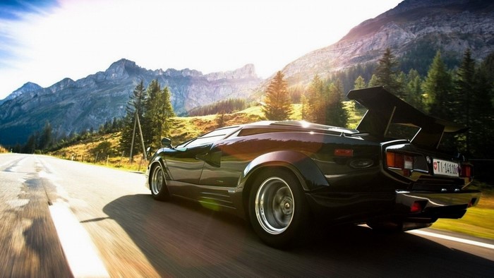 Black Lamborghini Countach driving on a mountain road