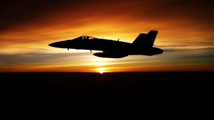 Silhouette of a fighter jet at sunset