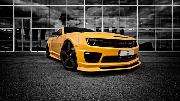 Yellow Chevrolet Camaro parked in front of a modern building