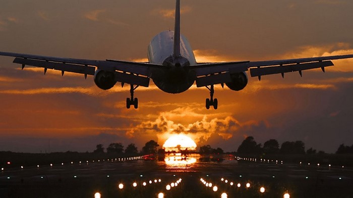 Airplane landing at sunset on runway