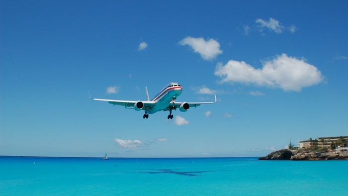 Airplane flying over turquoise ocean