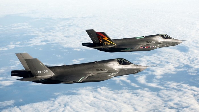 Two F-35 fighter jets flying over clouds