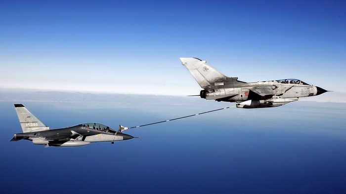 Fighter jets performing air-to-air refueling over the ocean