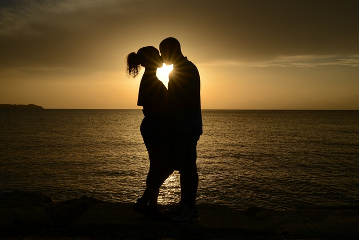 Couple kissing at sunset over the ocean