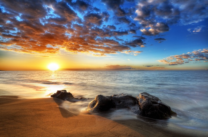Sunset over the ocean with rocks on the shore 4K