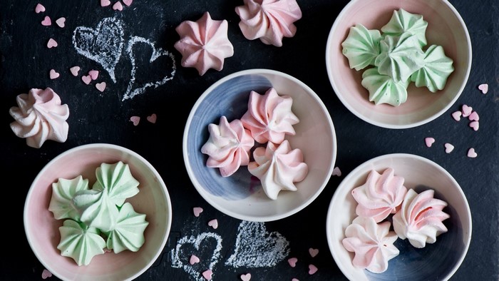 Pink and green meringues in bowls with chalk hearts