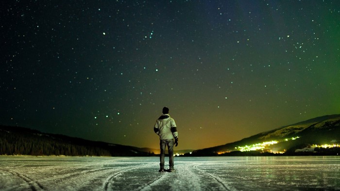 Man on frozen lake looking at stars