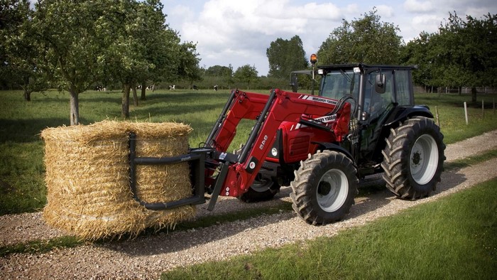 Massey Ferguson tractor carrying a hay bale