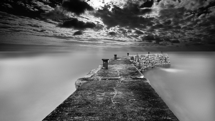Concrete pier with bollards under a cloudy sky