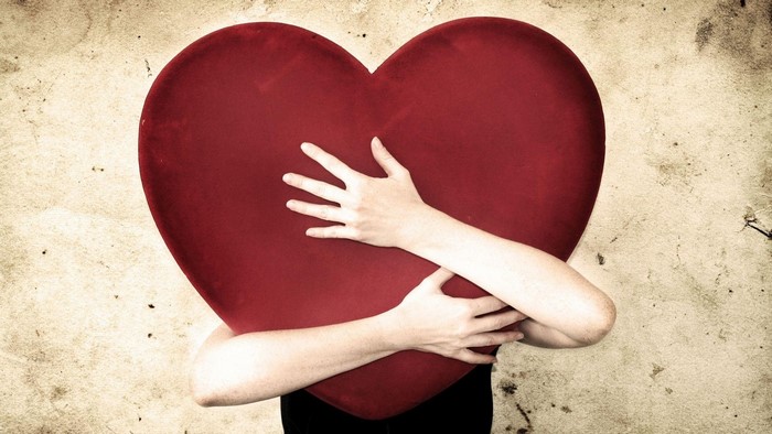 Person hugging a large red heart