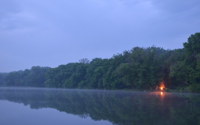 Campfire on a misty lake at dusk