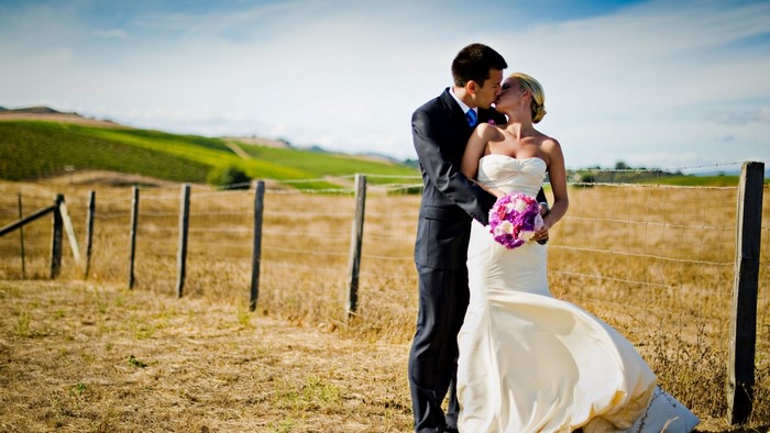 Couple kissing in a field with vineyards
