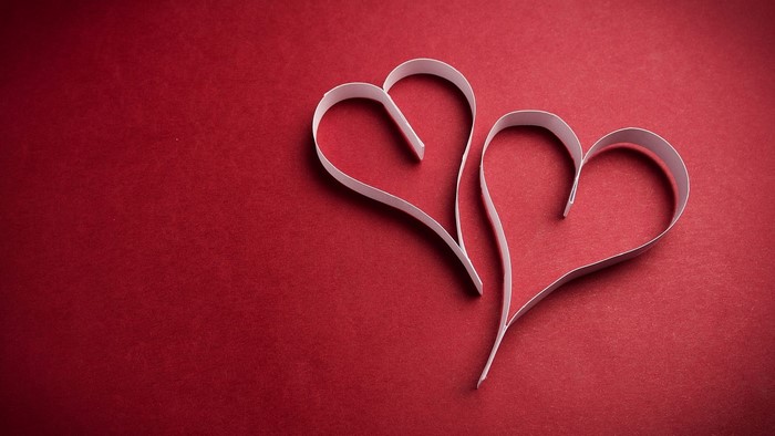 Two white paper hearts on a red background