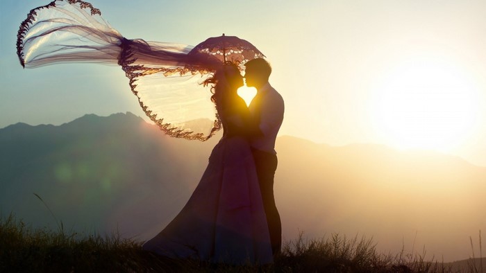 Couple kissing at sunset with veil and umbrella