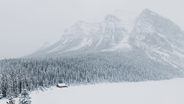 Winter mountain scene with forest and cabin
