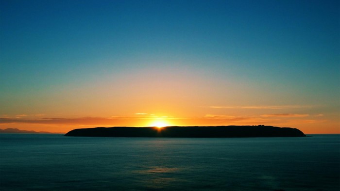 Island silhouette at sunset over the ocean