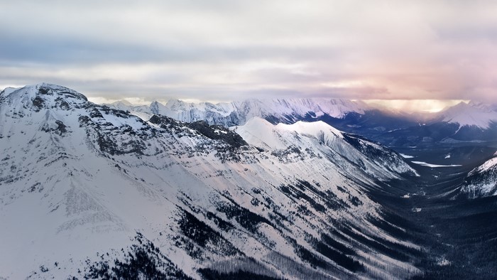 Snowy mountain range with distant storm clouds