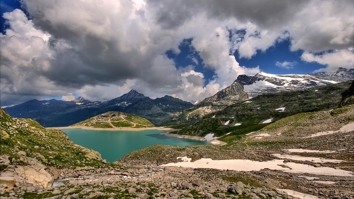 Turquoise lake and snowy mountains under cloudy sky