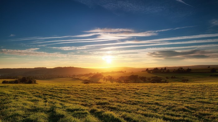 Sun rising over rolling green hills