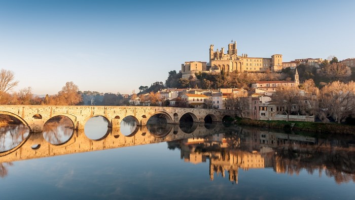 Stone bridge over a river with a fortress town on a hill
